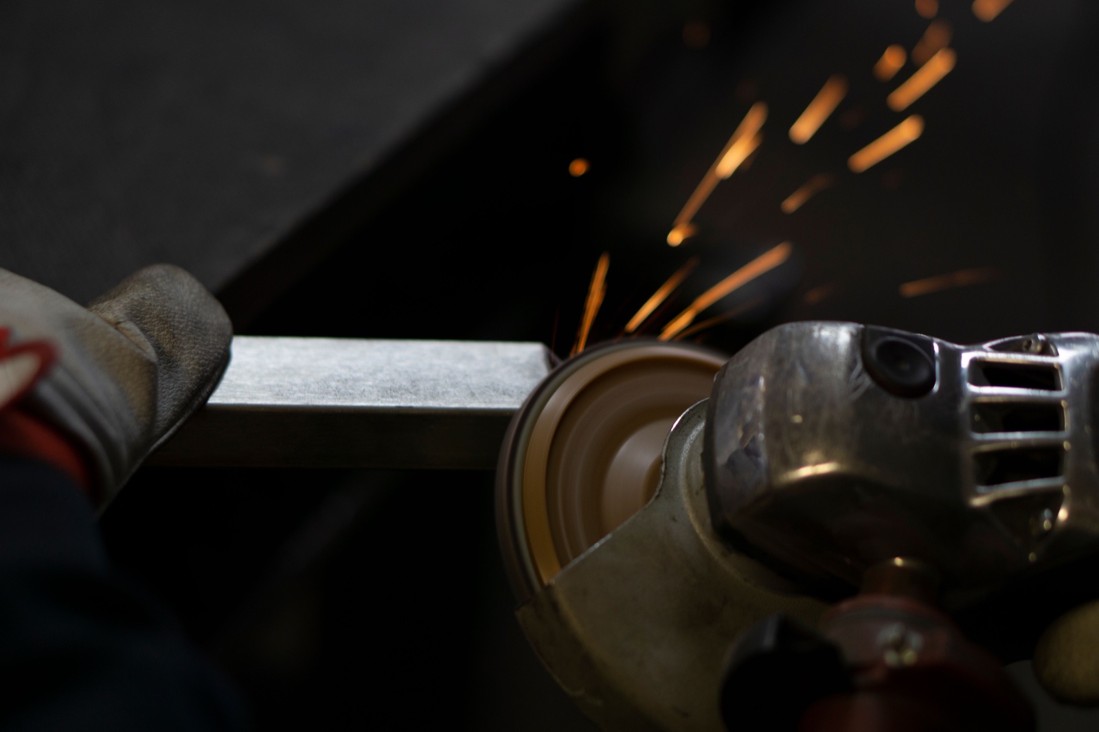 A worker grinding the edge of a steel component