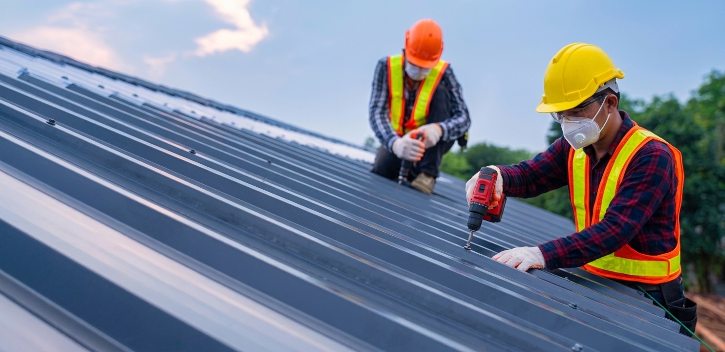 Construction workers installing prepainted steel roofing